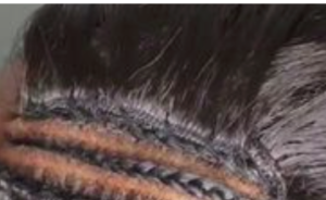 Black hair weft sewn on a track of braided hair.